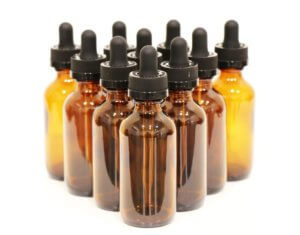 Ten amber bottles with black squeezable dropper caps to represent fragrance technology for an article about multi-sensorial products