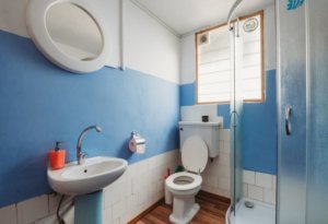 A blue and white bathroom with toilet, sink and shower for a fragrance article about air fresheners specifically formulated for toilets