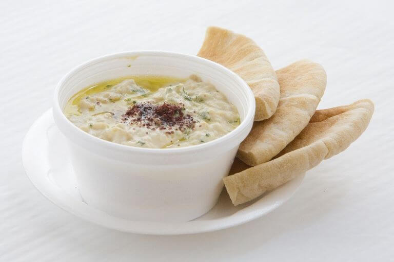 A white bowl of hummus and pita for an ingredient article about Middle Eastern flavors with a focus on chickpeas and hummus