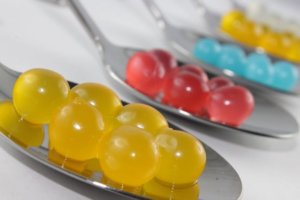 Close up of three silver spoons with edible yellow, red and blue beads for a multi-sensory article about molecular gastronomy