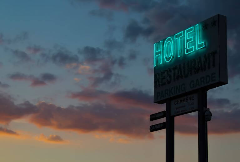 A turquoise neon hotel sign for an article about interactive themed hospitality and travel experiences