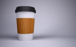 A white paper to go coffee cup with a corrugated wrap and black lid for an article about convenient products and services