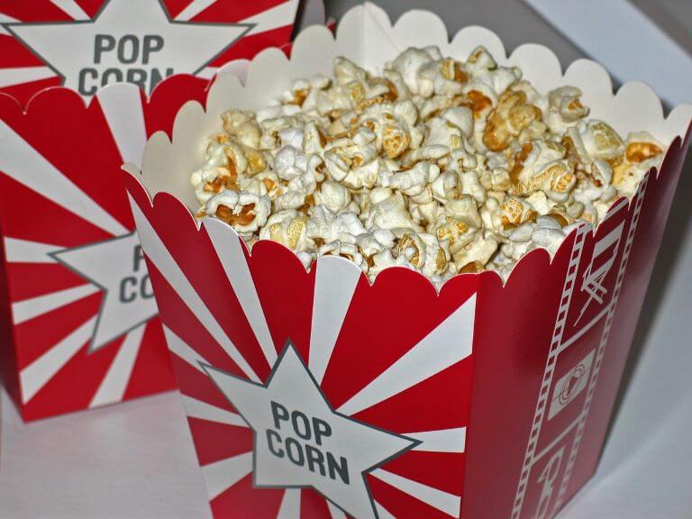 A close up of two red and white cartons of movie popcorn for an ingredient article about new popcorn flavors in beverages and desserts