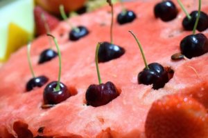 Close up of a watermelon with cherries stuck on top for an ingredient article about watermelon and cherry fragrances and flavors