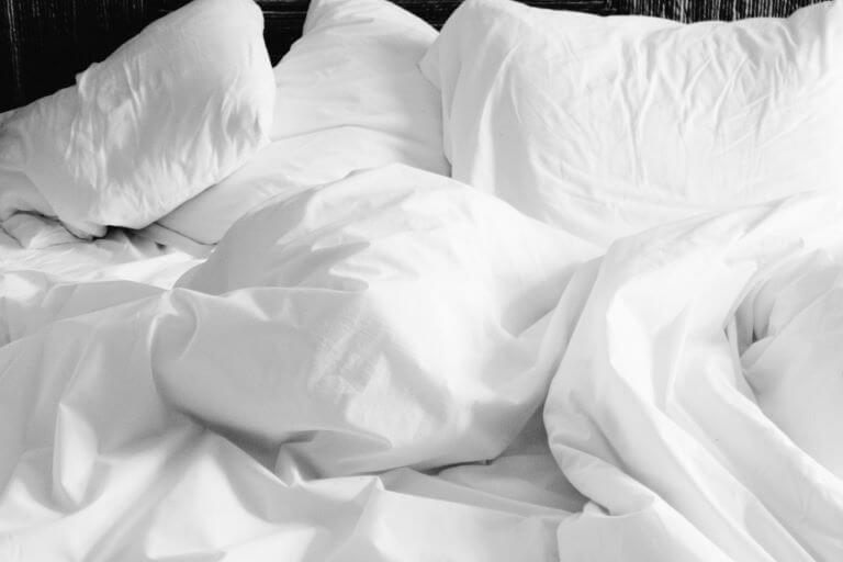 A unmade bed with white sheets and pillows for a lifestyle article about new sleep products