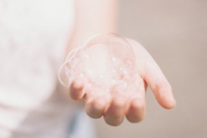 A close up of a woman's hand with a soap bubble for a health and wellness article about antibacterial and sanitizing products