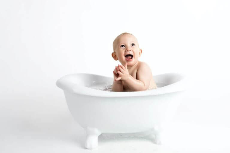 A happy baby in a white bathtub to depict clean hair and skin care formulas for babies and kids