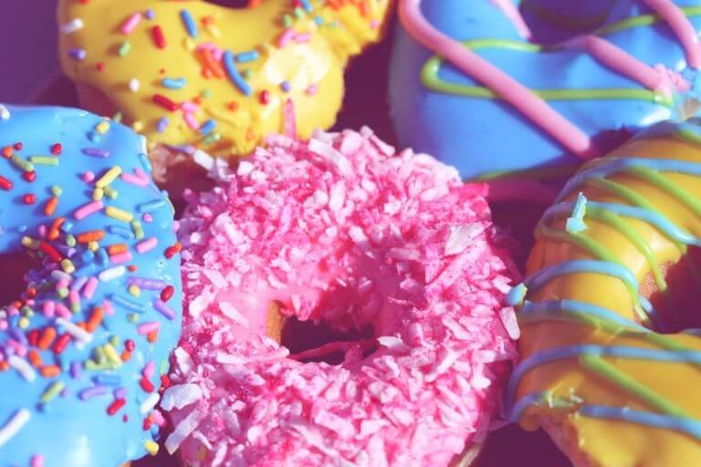 Close up of colorful pink, turquoise and yellow donuts with sprinkles for a trend article on donut flavors