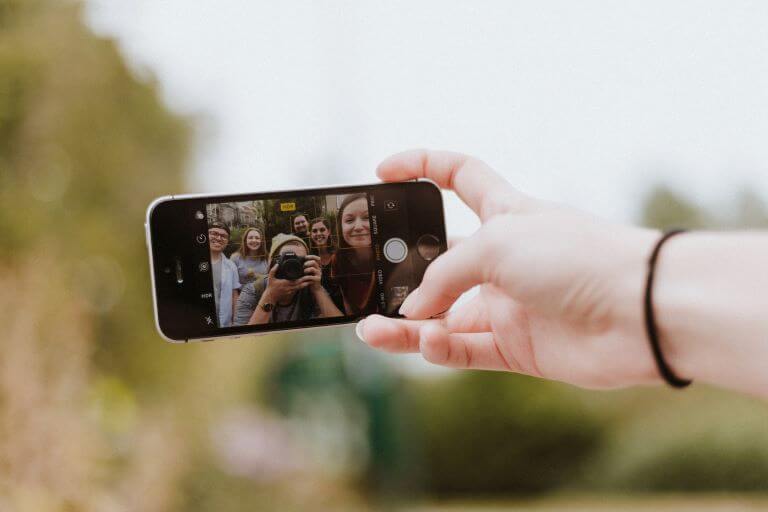 Selfie on mobile phone that shows group of young Gen Z demographic in photo with a camera taking picture