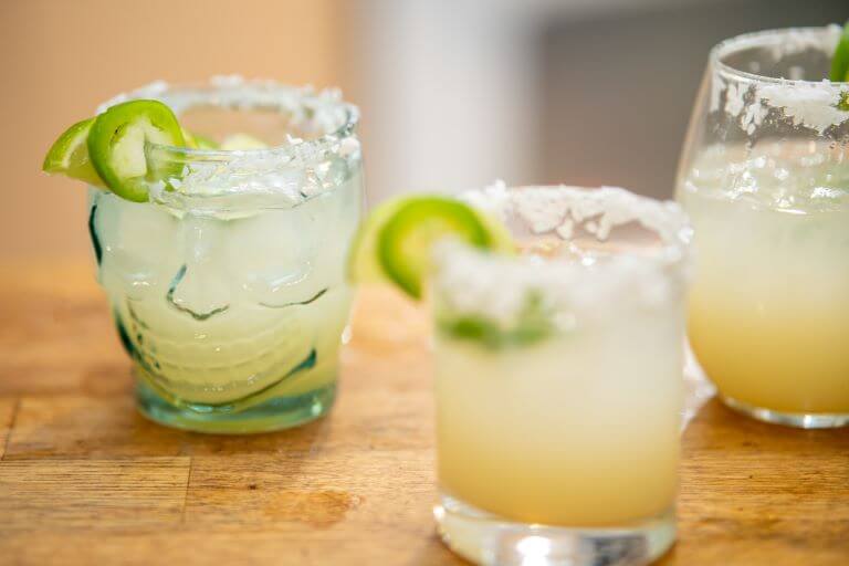 Three margaritas with salt and limes for a trend article about ready to drink canned cocktails and alcohol trends
