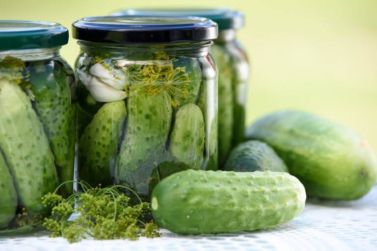 Pickles in pickle jar with cucumbers for article about pickle flavors appearing in unusual food and beverages