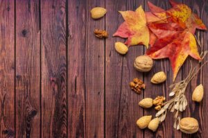 Brown wood background with fall leaves and nuts for 3 fall food and beverage trend article