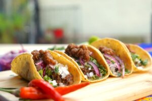 Four beef tacos with onion, cheese and cilantro for taco trends article