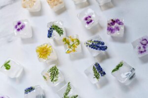 Colorful floral infused ice cubes scattered for a trend article about specialty ice and infused ice with fruits and flowers