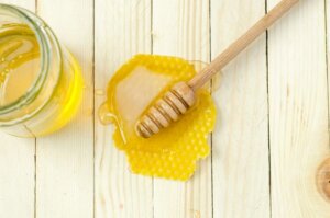 Honey comb with wooden honey stick and a jar of honey for trends article about honey products in flavors and fragrances