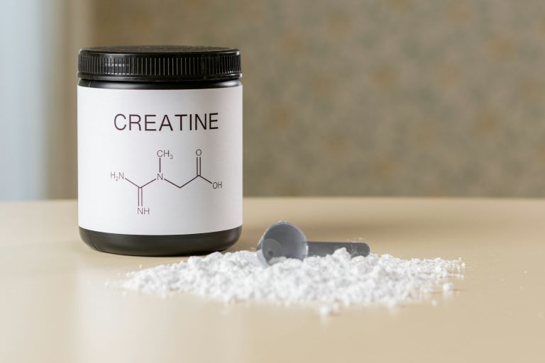 Creatine powder with scooper tan background for trend article about the popularity of nutrition and sports products